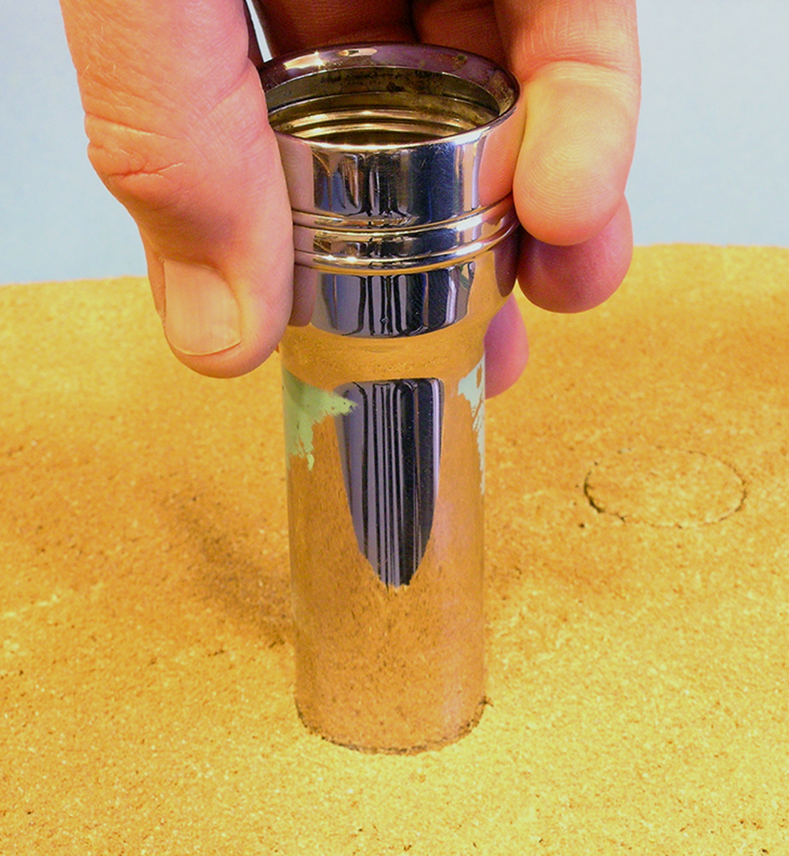 A hand presses a flashlight housing into a model railroad layout