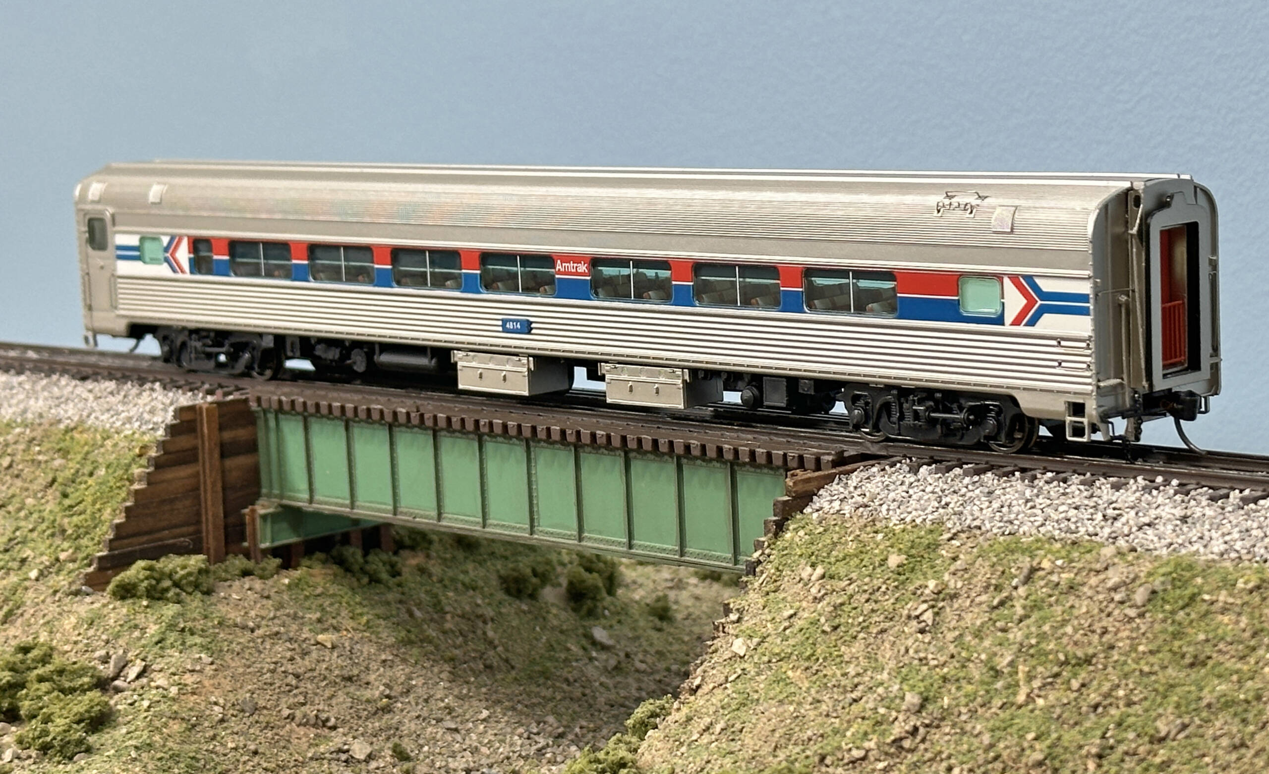 A silver model coach car with blue and red stripes along the side of the car