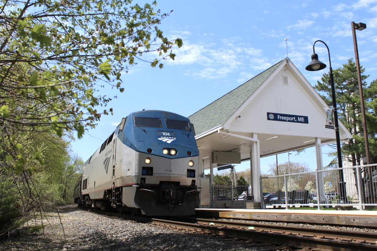 Low-angle view of passenger train at station platform with white wooden roof.