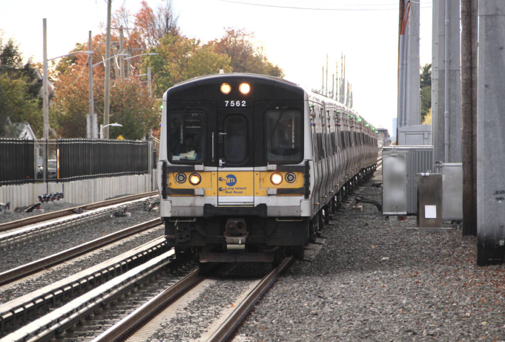 Electric multiple-unit trainset with yellow front approaching station on three-track main line