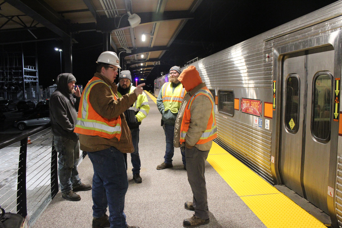 Men talking on station platform next to commuter train