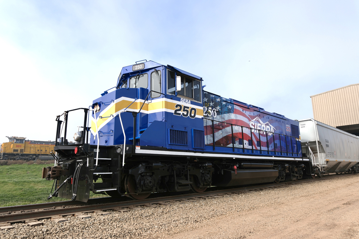 Blue, white, and gold locomotive with American flag design on long hood