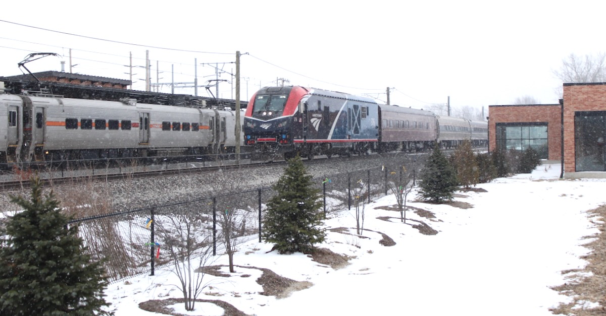 Amtrak train passes South Shore train at station