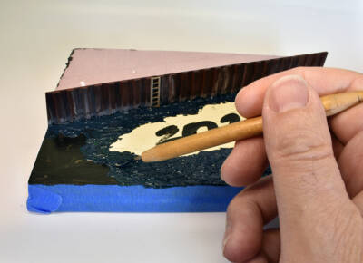 greenish-blue oil paint is applied to a flat surface with a sculpting tool