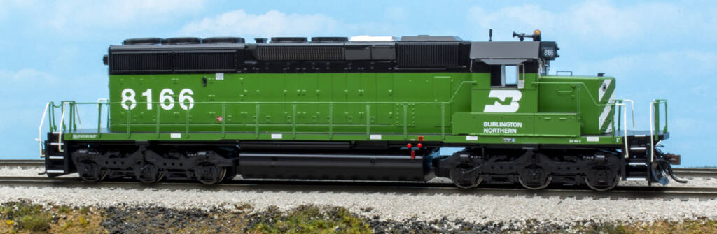 Color photo of HO scale EMD six-axle hood unit painted green and black with white graphics on scenicked base with a sky blue background.