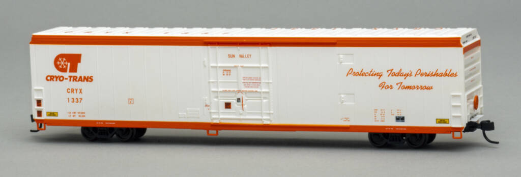 Color photo of N scale insulated boxcar painted white and orange with black trucks and couplers on gray background. 