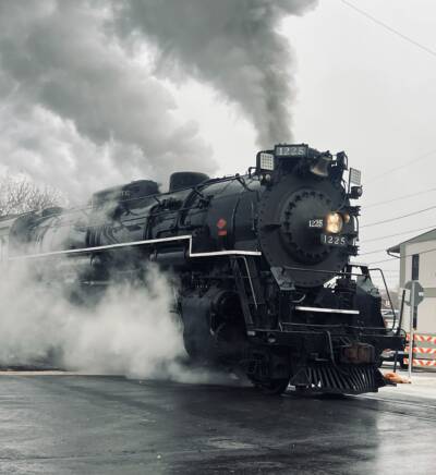 Steam locomotive departing on a cloudy day.
