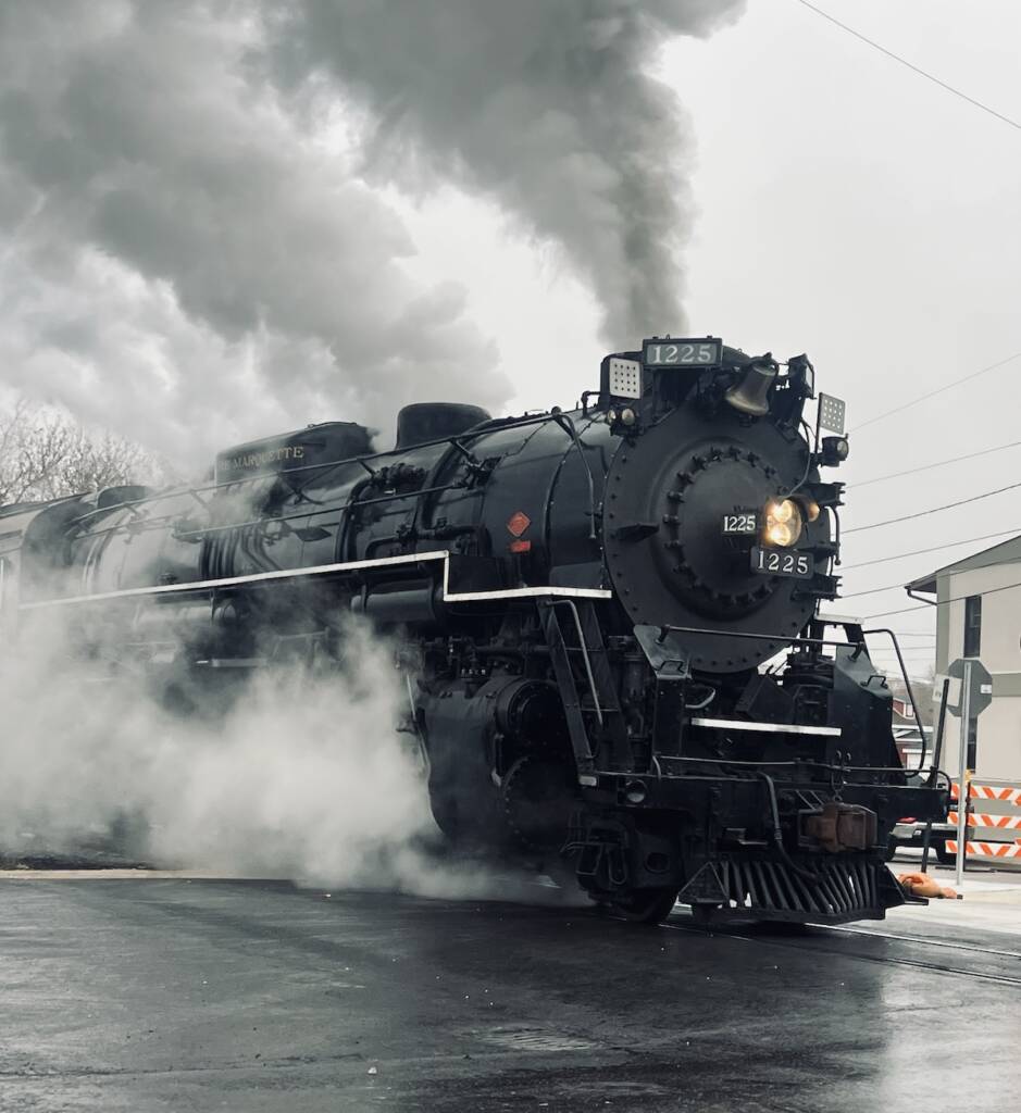 Steam locomotive departing on a cloudy day.