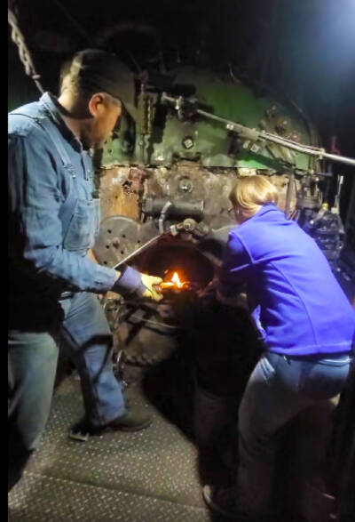 Man and woman lighting a fire in a steam locomotive firebox. Nevada Northern No. 81 fired … again.