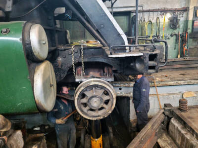 Front truck of a steam locomotive with workers adjusting it. Nevada Northern No. 81 fired … again.