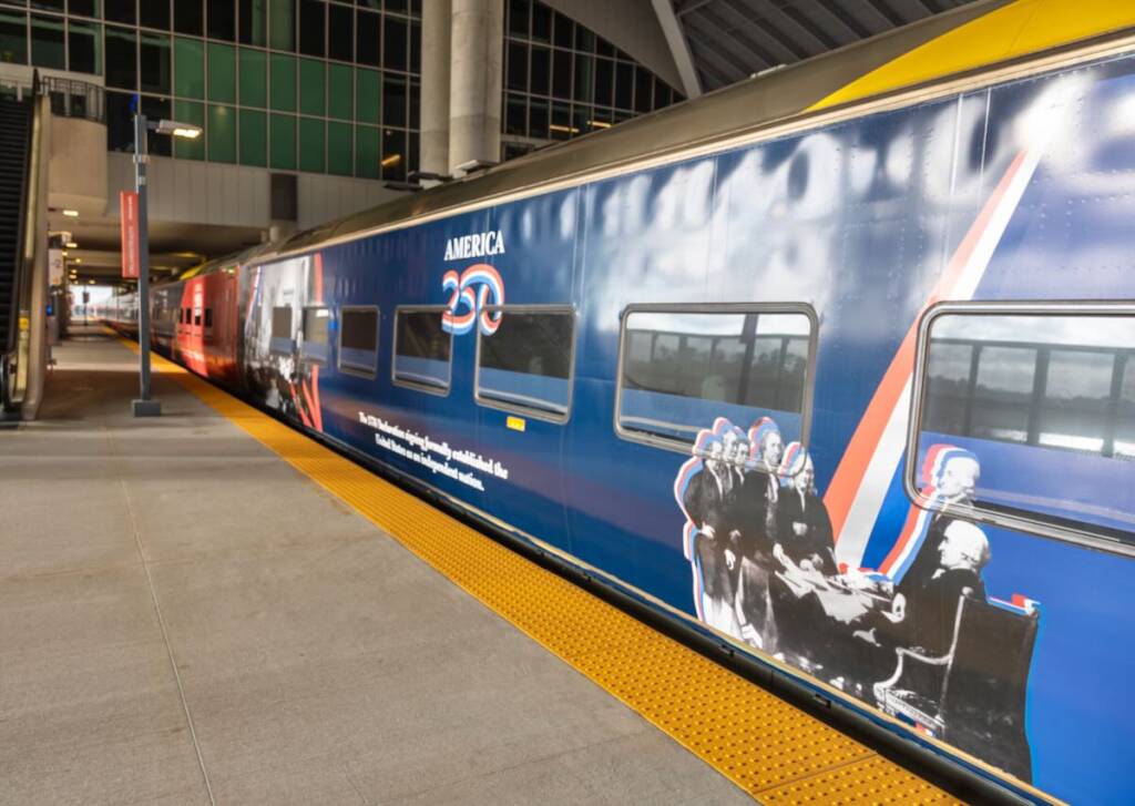 Blue passenger car with image of signing of Declaration of Independence in foreground.