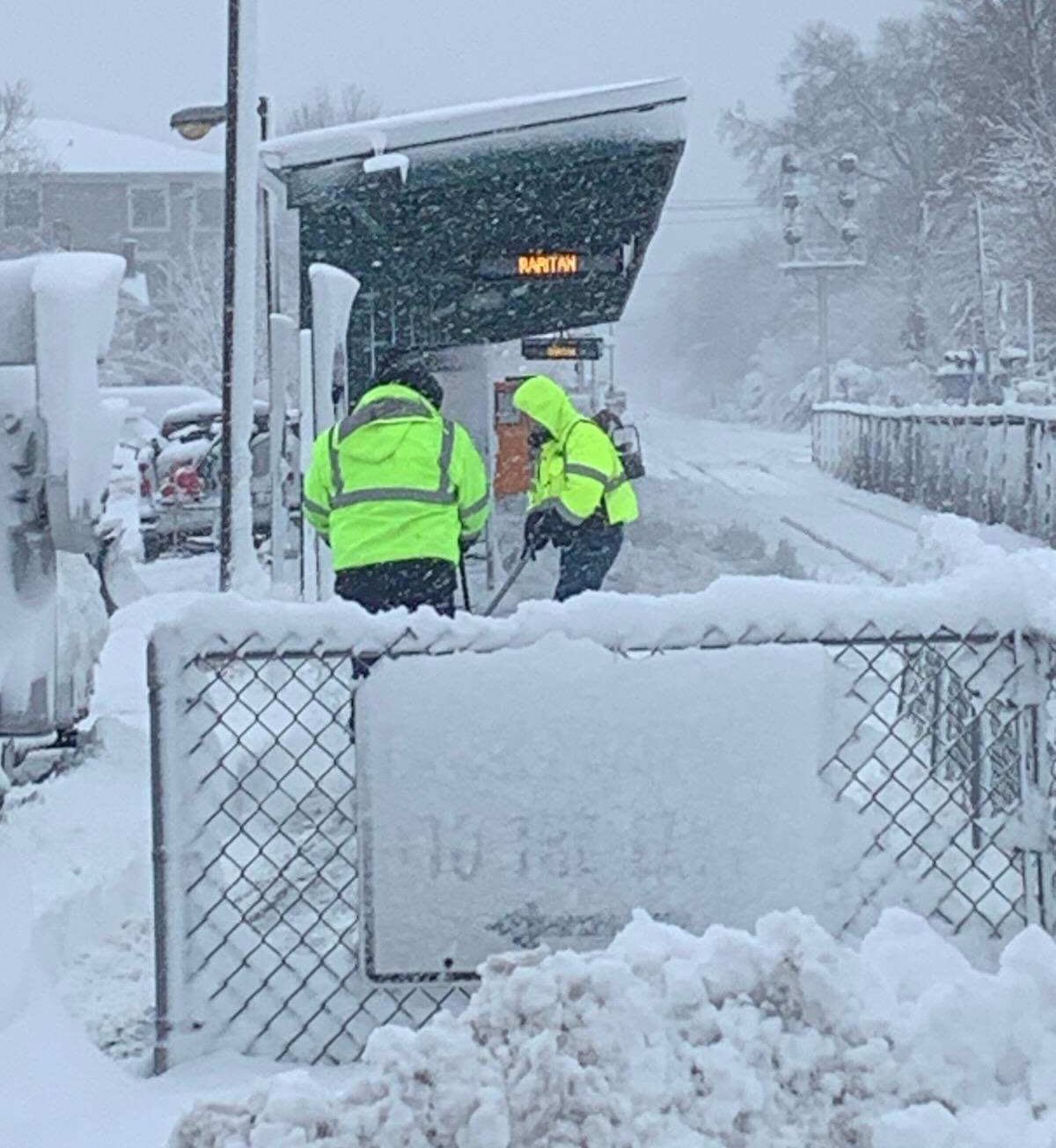 Men shoveling snow at commuter train station