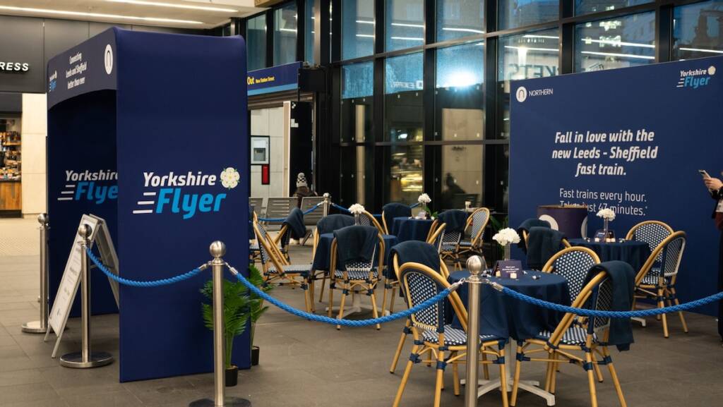 Tables and chairs in area at railroad station with "Yorkshire Flyer" signate