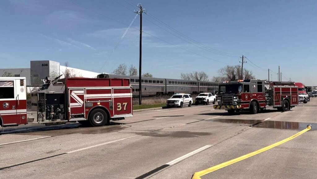 Fire trucks on roadway with train in background
