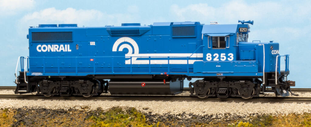 Color photo of HO scale EMD four-axle hood unit painted blue with white graphics and black trucks and fuel tank on scenicked base with a sky blue background.