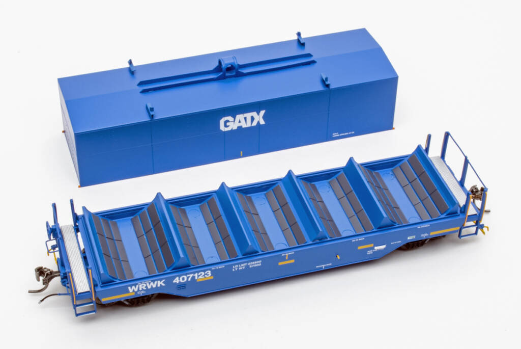 Color photo showing modern coil car with hood placed next to car on white background. The model is painted blue with yellow and white graphics and dark gray bunk liners.