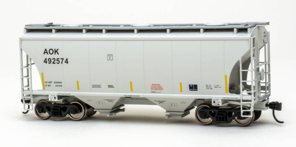 Color photo of modern HO scale two-bay covered hopper painted light gray with black, yellow, red, and white graphics; blackened metal wheelsets; silver running boards; and black trucks and couplers on white background. 