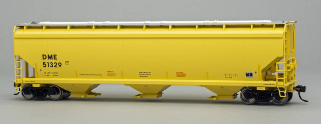 Color photo of HO scale three-bay covered hopper painted yellow with black and red graphics, silver running boards, white hatch covers, and black trucks on gray background.