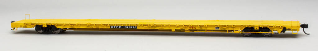 Color photo of HO scale 89-foot flatcar painted yellow with black, white, and red graphics on light gray background.