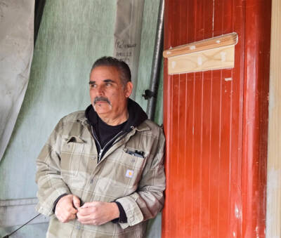 Man leaning against wall of passenger coach.