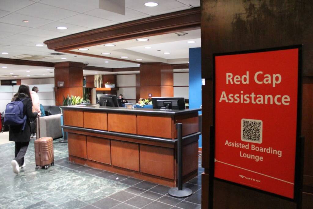 Counter at station next to sign labeled "Red Cap Assistance" with a QR code