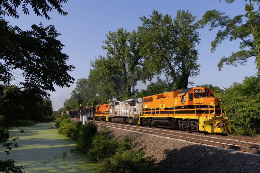 Train with two orange and black locomotives sandwiching one gray and white unit